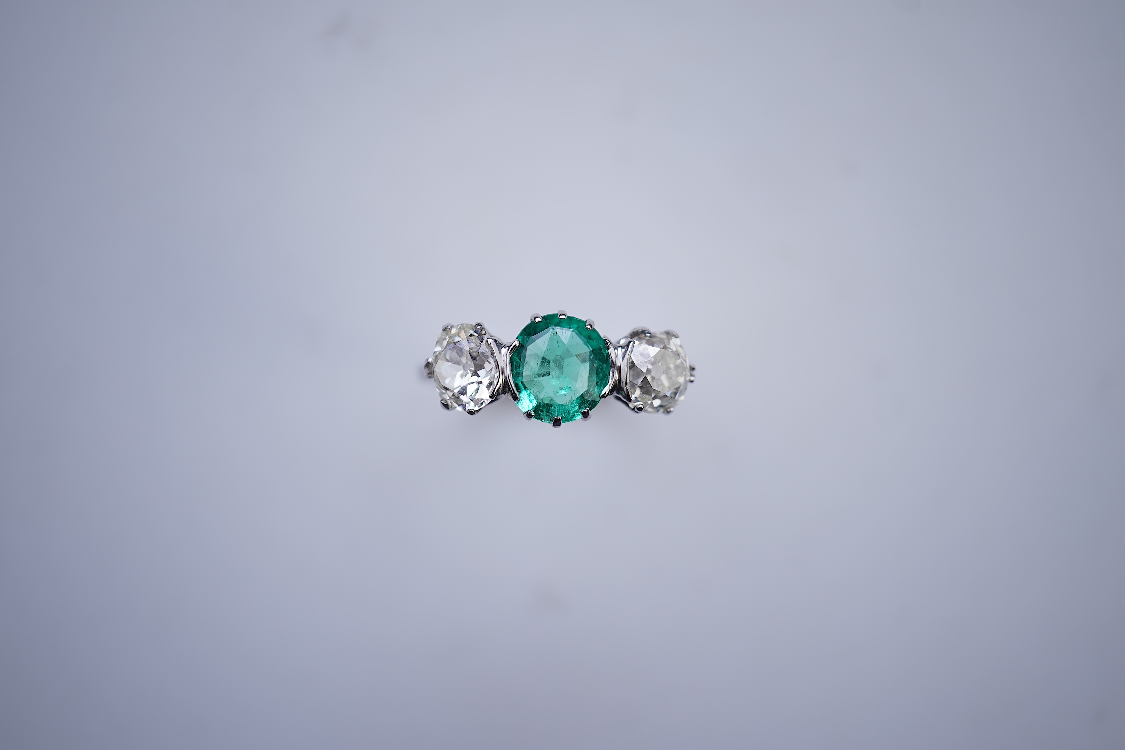 An attractive emerald and diamond three-stone ring, early 20th century